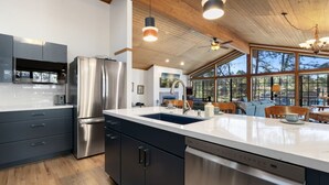 A modern kitchen with stainless steel appliances, a large island with a sink, and a dining area with a view.