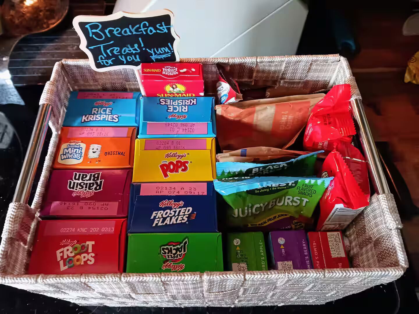 A basket filled with various breakfast cereals and snacks.