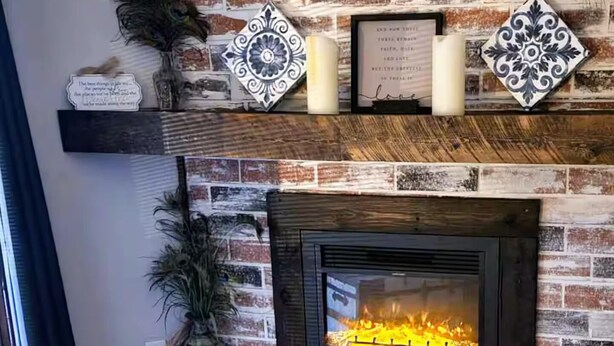 Lareira com parede de tijolos, azulejos decorativos e uma planta.