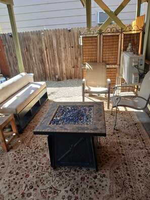A patio area with a fire pit, outdoor furniture, and a decorative fence.