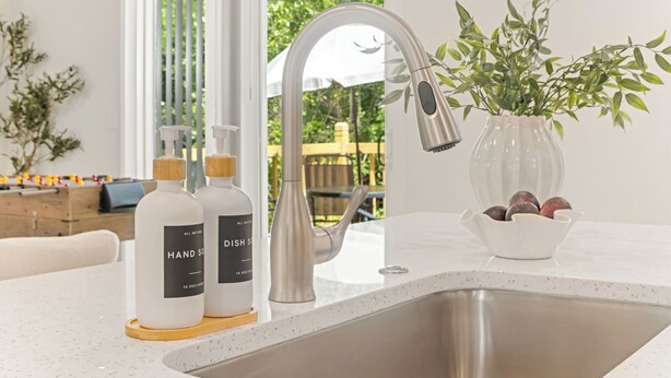 Eine moderne Küche mit Spüle aus Edelstahl, einem Wasserhahn und einem Blumenarrangement auf der Arbeitsfläche.