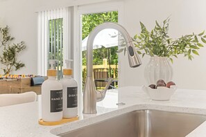 Een moderne keuken met een roestvrijstalen spoelbak, een kraan en een vaas met bloemen op het aanrecht.