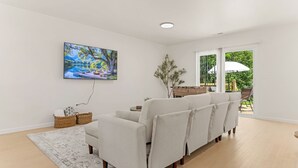 Ein modernes Wohnzimmer mit einer Couch, einem Gemälde und Blick ins Freie.