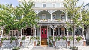 Stunning two-story building with a central entrance, ornate balcony, and white picket fence.