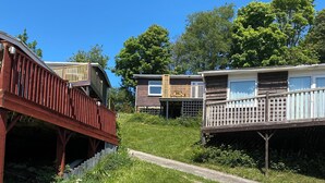 A campsite with wooden cabins, a covered walkway, and a grassy area. - Cosy holiday chalet (Cearnarfo)