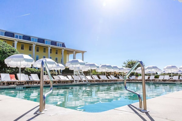 Relax by the pool surrounded by lounge chairs and shaded by umbrellas.