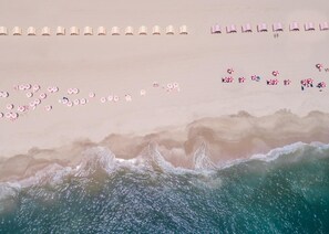 An aerial view of a beach with rows of beach umbrellas and lounge chairs. - King Guestroom with Continental Breakfast for Two | The Red Cottage (Cape May)