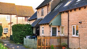 A row of traditional stone houses with pitched roofs, wooden fences, and potted plants. - Pet-friendly Countryside Holiday Home, No Deposit (Cheltenham)