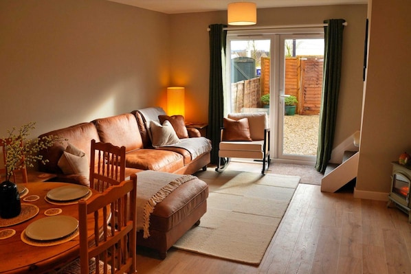 A cozy living room with a sofa, chairs, a dining table, and a fireplace.