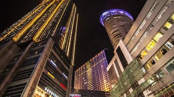 Vista nocturna de un paisaje urbano con edificios altos, incluyendo un edificio curvo distintivo con señalización iluminada.