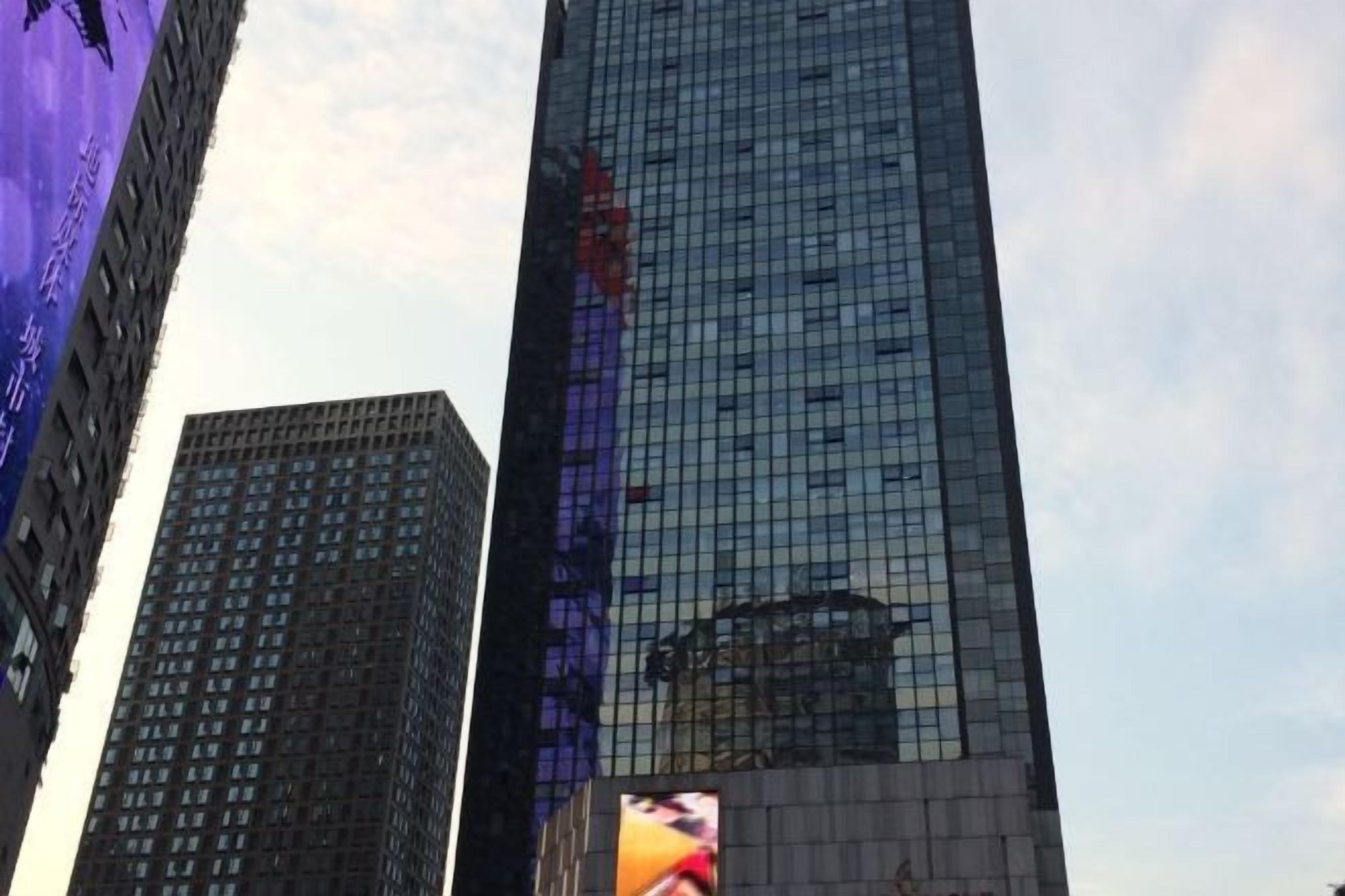 Un rascacielos alto y moderno con fachada de vidrio que refleja el cielo y edificios cercanos.