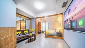 A modern hotel room with a sofa, a small table, and a sliding door leading to a balcony. - Qiyue Shangpin Cinema Hotel Apartment (Guanyinqiao Branch) (Chongqing)