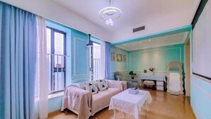 A living room with a sofa, a table, and a chair. - Qiyue Shangpin Cinema Hotel Apartment (Guanyinqiao Branch) (Chongqing)