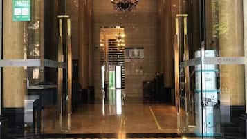Un hall de hotel con mostrador de recepción, un candelabro y una partición de vidrio.