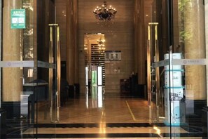 A hotel lobby with a reception desk, a chandelier, and a glass partition. - Qiyue Shangpin Cinema Hotel Apartment (Guanyinqiao Branch) (Chongqing)