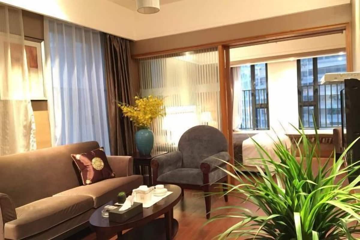 Une chambre d’hôtel avec un canapé, un fauteuil, une table basse et une grande plante.
