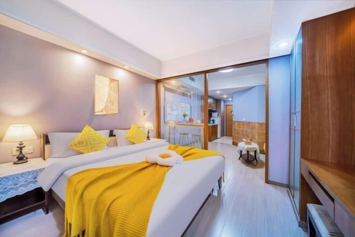 Une chambre d’hôtel moderne équipée d’un lit, de tables de chevet, d’un bureau et offrant une vue sur la cuisine.