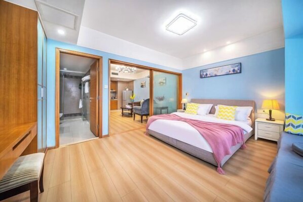 A bedroom with a bed, bedside table, and a desk with a chair.