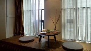 A room with a sofa, a small round table with books and a vase, and sheer curtains. - Qiyue Shangpin Cinema Hotel Apartment (Guanyinqiao Branch) (Chongqing)