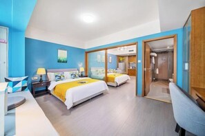 A hotel room with two beds, a desk, a chair, and a bathroom visible through a glass door.