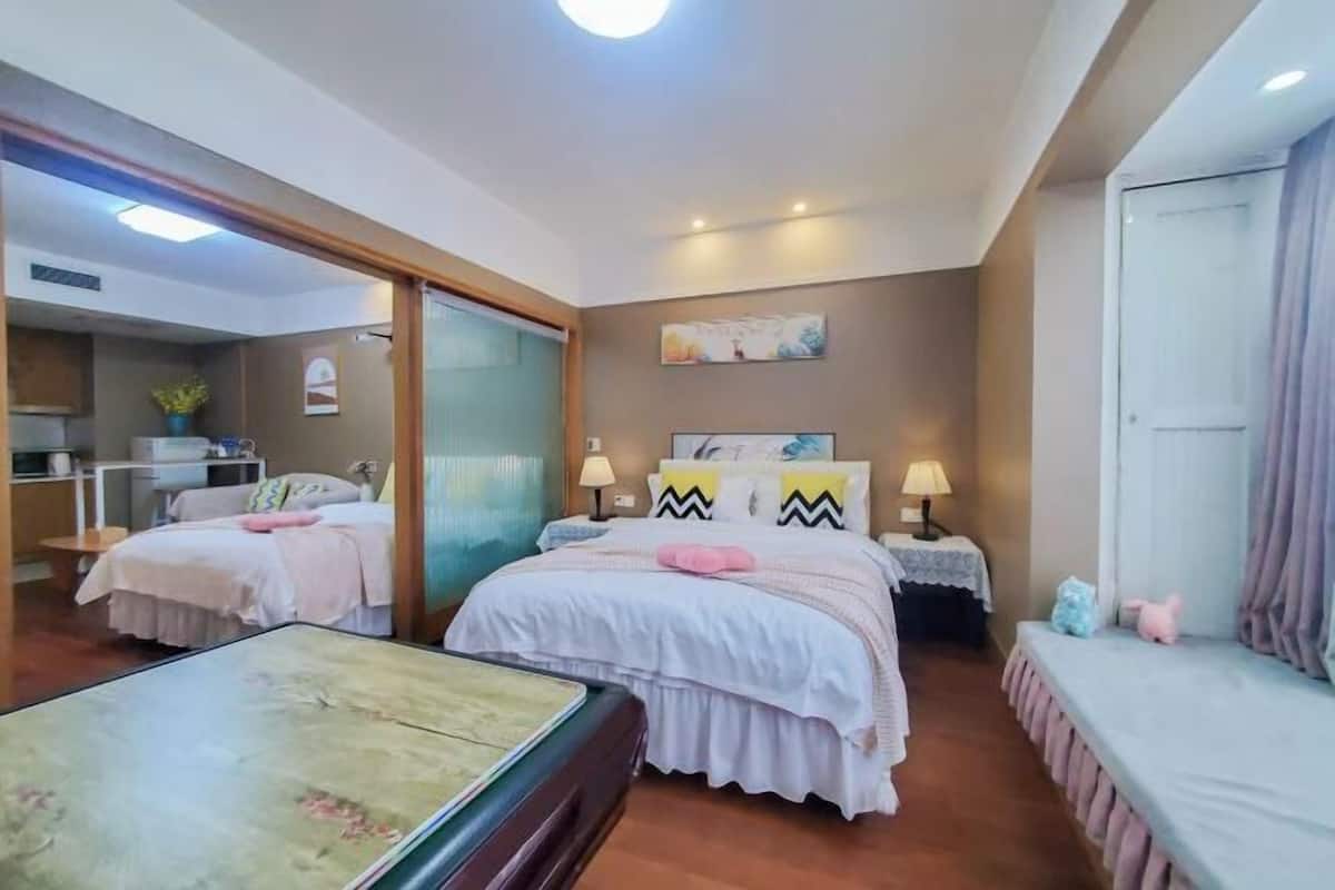 Une chambre d’hôtel avec deux lits, une petite table, un bureau et un miroir.