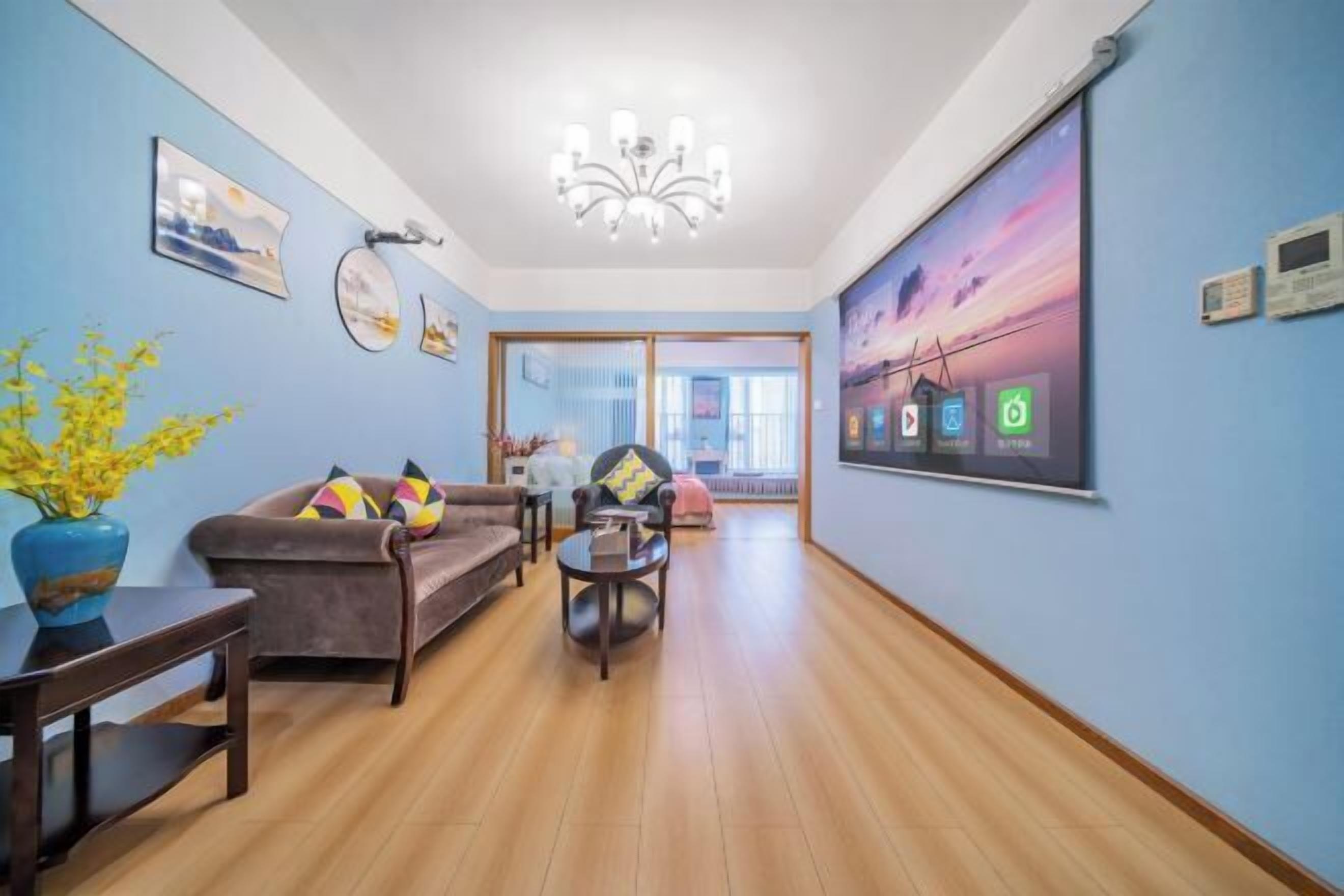 Amplia sala de estar con piso de madera, un sofá marrón, una mesa de centro y un cuadro grande en la pared.