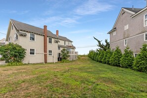 A residential area with two houses, a grassy yard, and a wooden fence. - Ocean Views|HOT TUB|Beach Access| Pet Friendly! (Kennebunk)