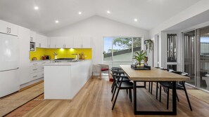 Enjoy meals in the kitchen with a central island and dining area featuring a wooden table and black chairs.