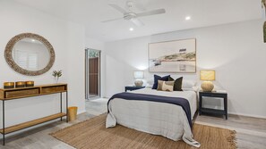 Relax in a serene bedroom with a large bed, round mirror, and a beautiful landscape painting.