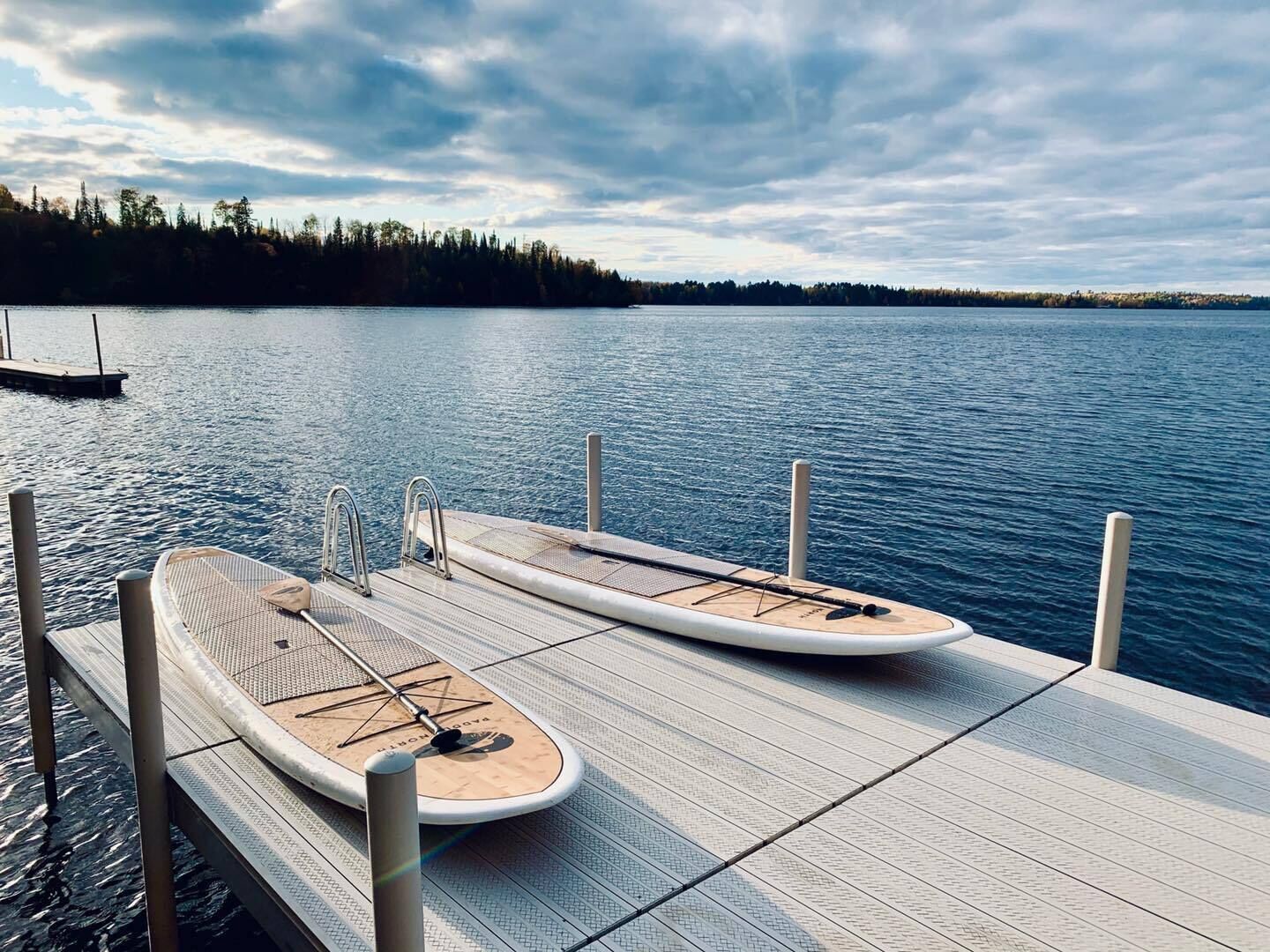 A wooden dock with two paddleboards.