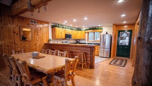 A wooden cabin-style kitchen with a central island, wooden chairs, and a dining table. - Timber Bay Lodge & Houseboats (Babbitt)