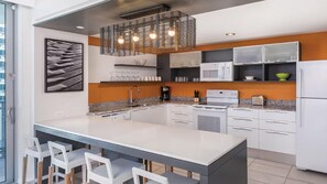 Una cucina moderna con isola centrale, mobili bianchi e una lampada a sospensione.