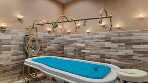 Une salle de bain moderne avec une baignoire sur pieds, une douche à plusieurs jets et un luminaire fixé au mur.