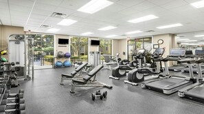 Une salle de sport équipée de machines de cardio, de matériel de musculation et de ballons d’exercice.