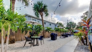 A patio area with outdoor seating, palm trees, and string lights. - Blushing Flamingo- Pool + Putting, Walk to Beach (Indian Rocks Beach)