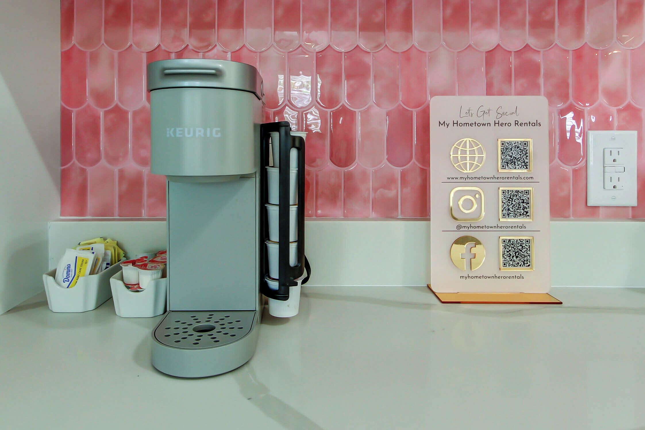 Una cafetera, un refrigerador y un letrero con códigos QR e iconos de redes sociales.
