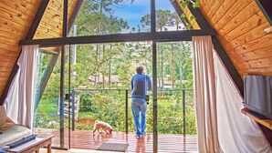 A person standing on a balcony with a dog, overlooking a forested area. - Chalet Mon Amour 1 - Pure design in pure air. Hydro, fire pit, pet friendly (Jd do Embaixador Campos do Jordão)