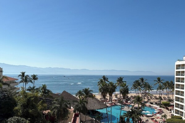 A resort with a pool, palm trees, and a view of the ocean.