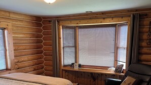 A log cabin room with a bed, a leather chair, and a window with blinds. - Charming 3-bedroom cabin in Victor only 25 miles from Jackson Hole, pet friendly (Victor)