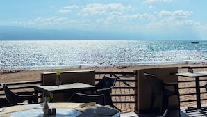 Un café situé en bord de mer, avec une terrasse offrant une vue sur l’océan.