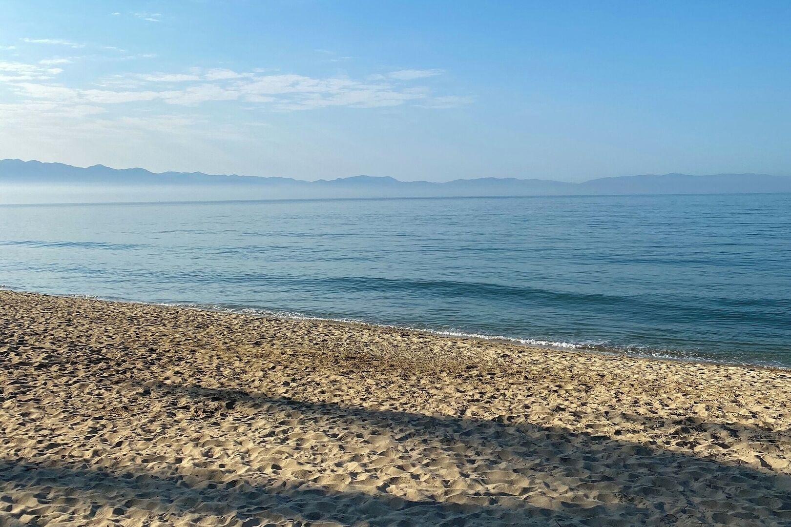 Ein Strand mit kiesigem Ufer und ruhigem Wasser.