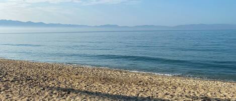 A beach with a pebbly shore and calm water.