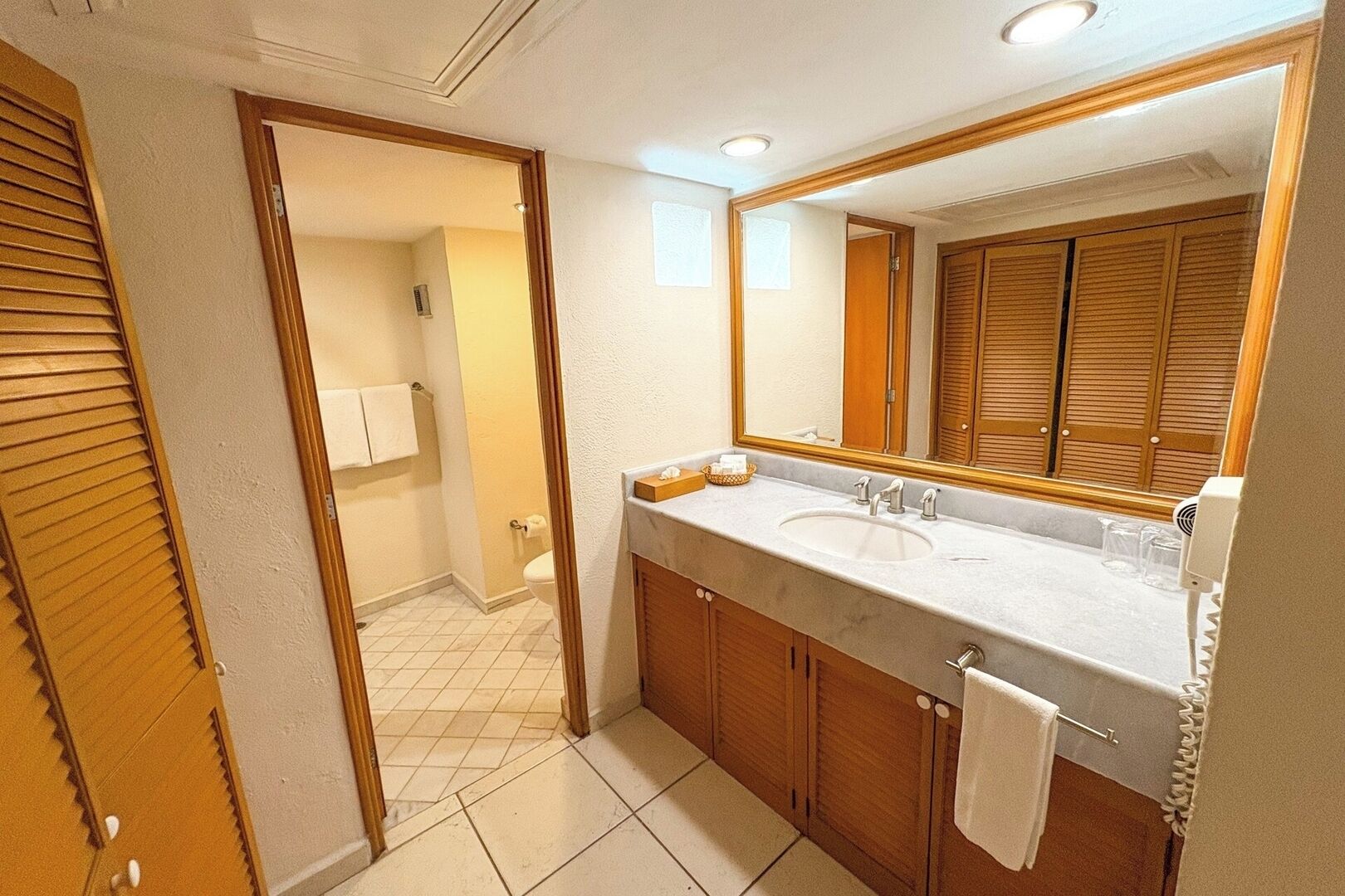 A bathroom with a wooden vanity, a large mirror, and a sink.