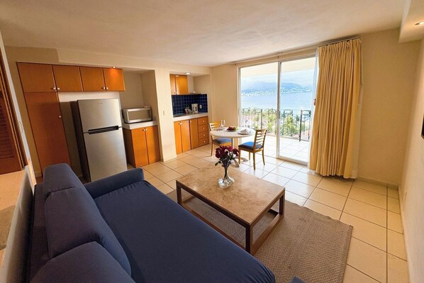 Una habitación de hotel moderna con cocina, comedor y balcón con vistas.
