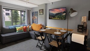 A modern living room with a sofa, dining table, chairs, and a ceiling fan.