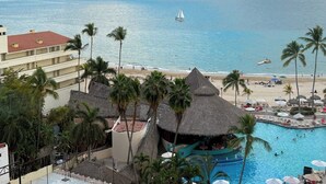 A resort with a pool, beach, and palm trees.