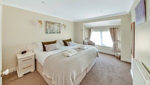 A bedroom with a large bed, bedside tables, a nightstand, a window with curtains, and a radiator. - Cottage in Thirsk With Private Hot Tub (Thirsk)