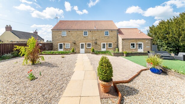 A two-story stone house with a tiled roof, a gravel driveway, and a small garden with potted plants. - Cottage in Thirsk With Private Hot Tub (Thirsk)