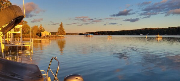 A calm lake with boats, a dock, and a building on the shore.