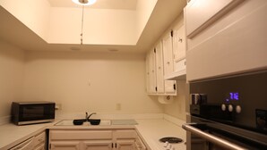 A compact kitchen with white cabinets, a microwave, a sink, and a stove.